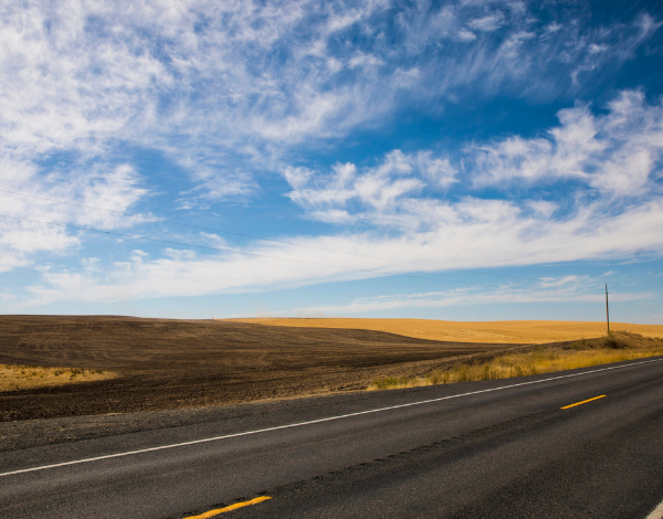 An empty road in the desert under a cloudy sky